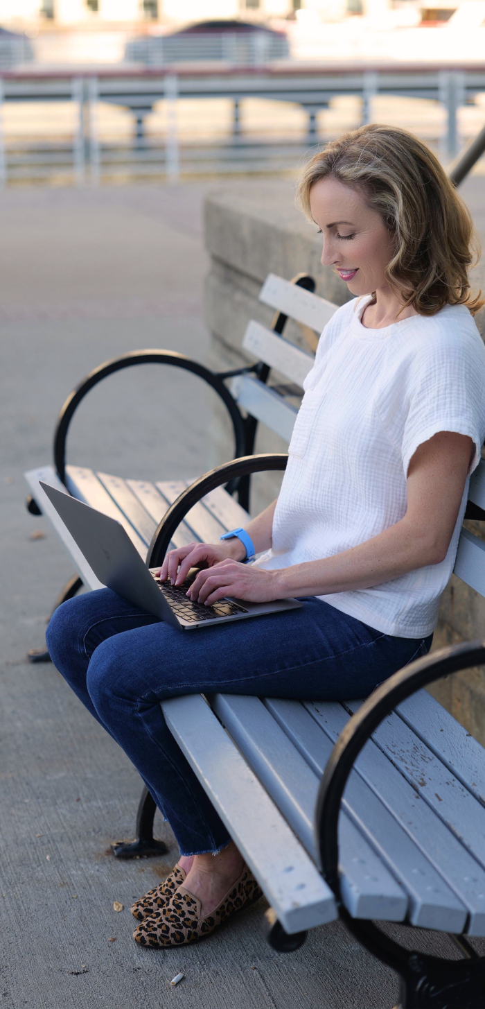 Photo of Dale Seabury working on her laptop on a park bench